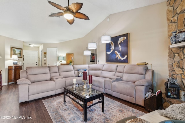 living room featuring ceiling fan, dark hardwood / wood-style floors, vaulted ceiling, and a stone fireplace