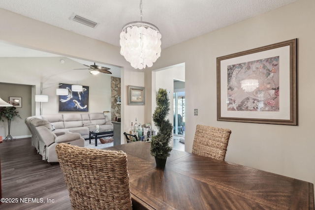 dining space with lofted ceiling, dark hardwood / wood-style floors, ceiling fan with notable chandelier, and a textured ceiling