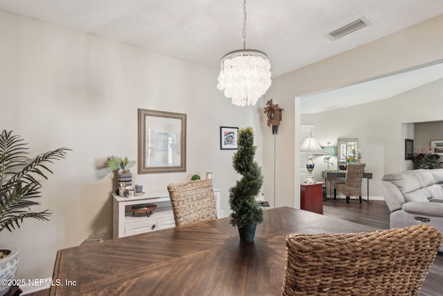 dining space featuring an inviting chandelier, a textured ceiling, and dark hardwood / wood-style flooring