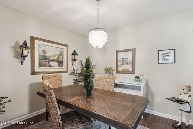 dining space featuring dark wood-type flooring, a chandelier, and a textured ceiling