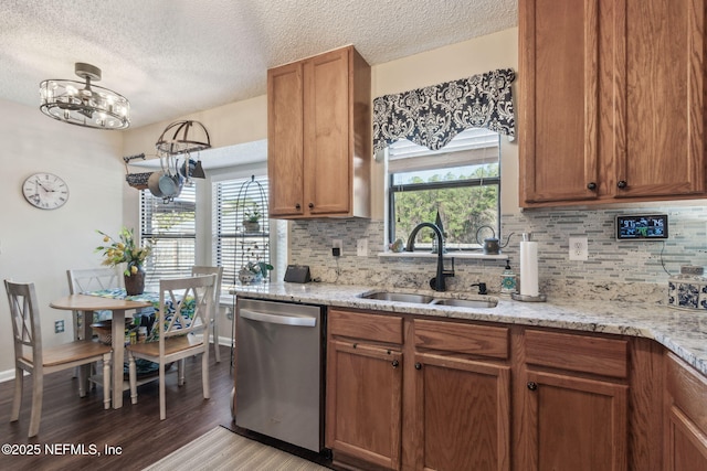 kitchen with a healthy amount of sunlight, sink, light stone countertops, and dishwasher