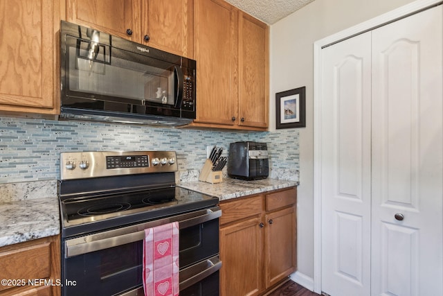 kitchen featuring double oven range, light stone countertops, a textured ceiling, and backsplash