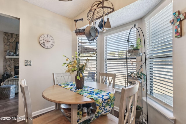 dining room featuring a stone fireplace, hardwood / wood-style floors, and a textured ceiling