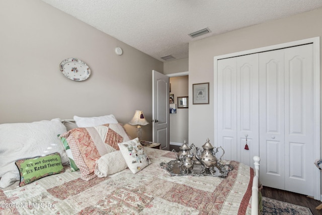 bedroom with dark hardwood / wood-style floors, a textured ceiling, and a closet