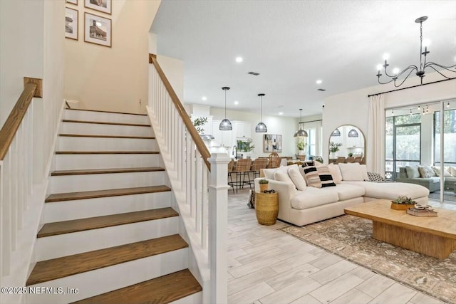 staircase with hardwood / wood-style floors and a notable chandelier