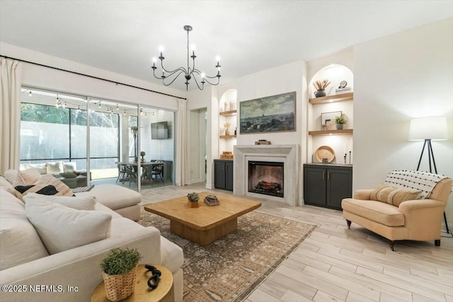 living room featuring light wood-type flooring, an inviting chandelier, and built in shelves