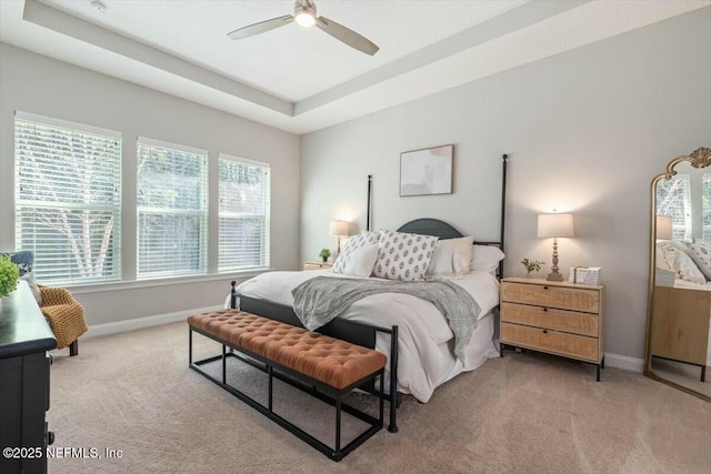 carpeted bedroom with a raised ceiling and ceiling fan