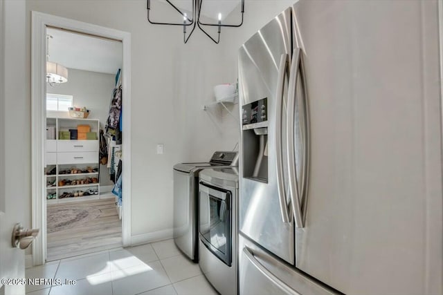 washroom with washing machine and clothes dryer, light tile patterned floors, and a notable chandelier