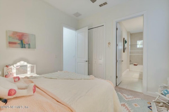 bedroom with connected bathroom, light carpet, and a closet