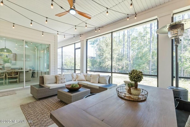 sunroom / solarium with ceiling fan, track lighting, and a wood stove