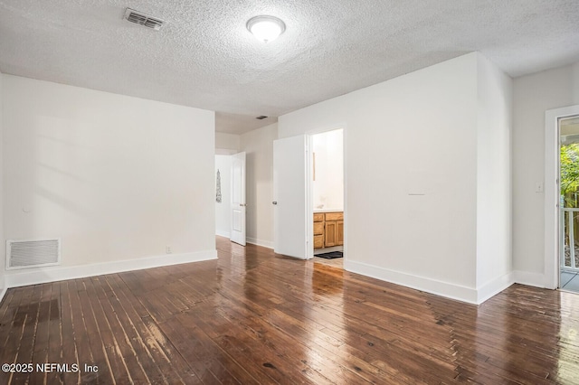 empty room with a textured ceiling and dark hardwood / wood-style flooring