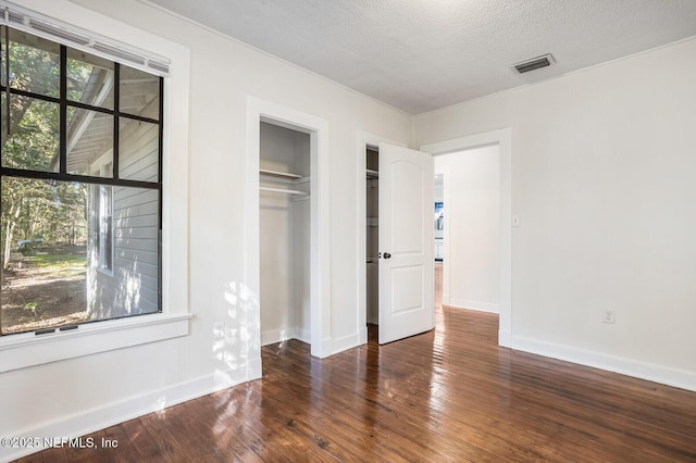 unfurnished bedroom featuring dark wood-type flooring, a textured ceiling, and a closet