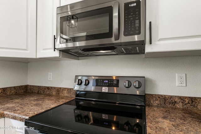 kitchen featuring electric stove and white cabinetry