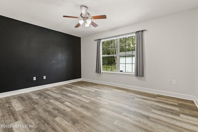 spare room with ceiling fan, a textured ceiling, and light wood-type flooring