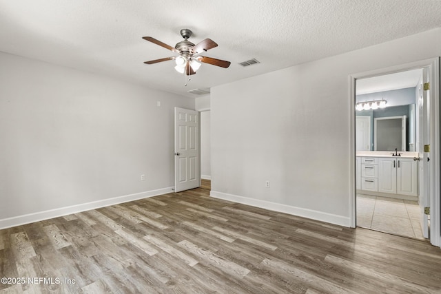 unfurnished room featuring hardwood / wood-style floors, sink, a textured ceiling, and ceiling fan