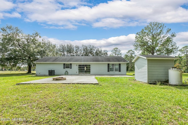 back of house with a fire pit, a lawn, central air condition unit, and a patio area