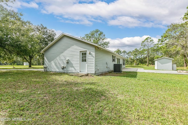 view of home's exterior featuring a storage shed, a yard, and central AC