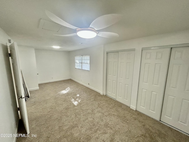 unfurnished bedroom featuring carpet floors, two closets, and ceiling fan