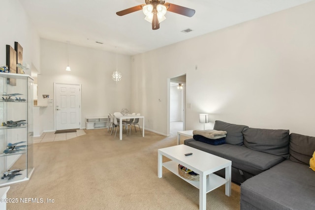 carpeted living room with ceiling fan and a towering ceiling