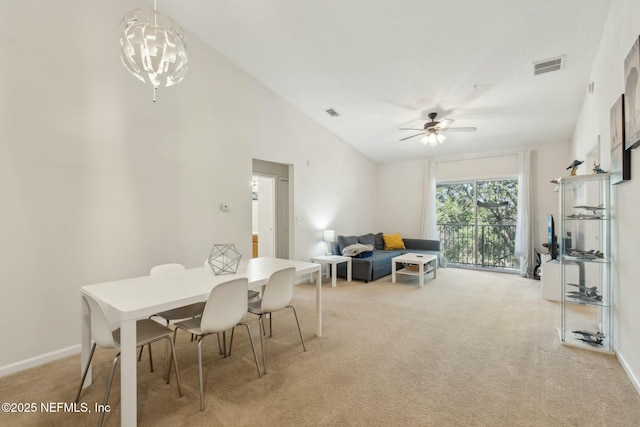 dining room with light carpet, ceiling fan with notable chandelier, and lofted ceiling