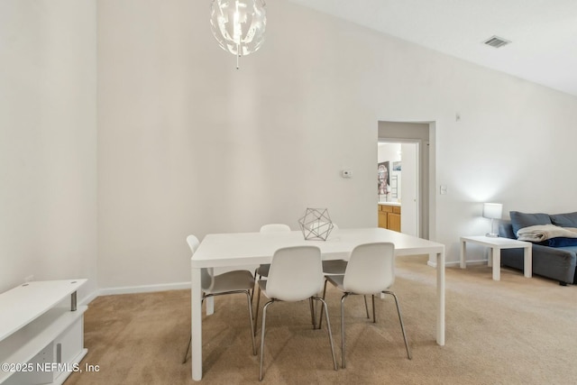 dining space featuring light carpet, lofted ceiling, and a chandelier