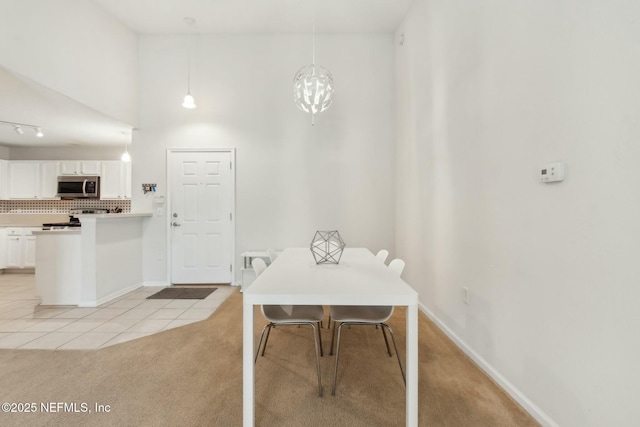 dining space featuring light carpet and a towering ceiling