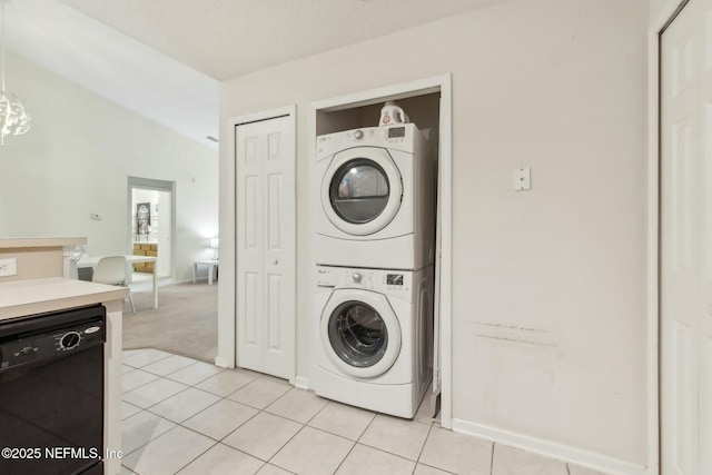 laundry area with stacked washing maching and dryer and light tile patterned floors