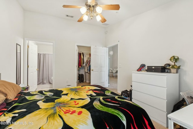 bedroom featuring connected bathroom, a spacious closet, light colored carpet, ceiling fan, and a closet