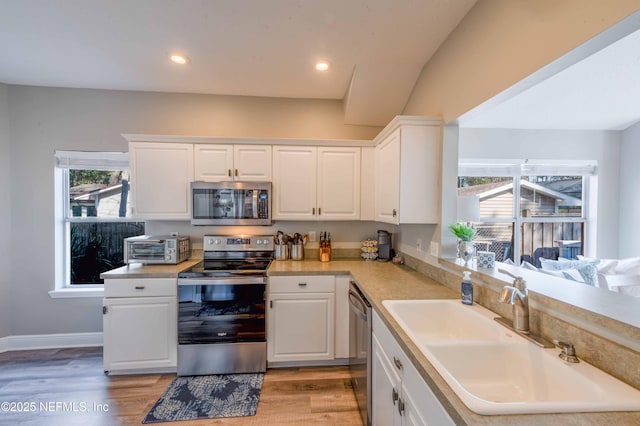 kitchen featuring white cabinetry, sink, light hardwood / wood-style flooring, and appliances with stainless steel finishes