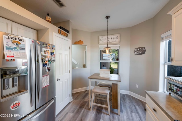 kitchen featuring pendant lighting, stainless steel fridge with ice dispenser, dark wood-type flooring, and white cabinets