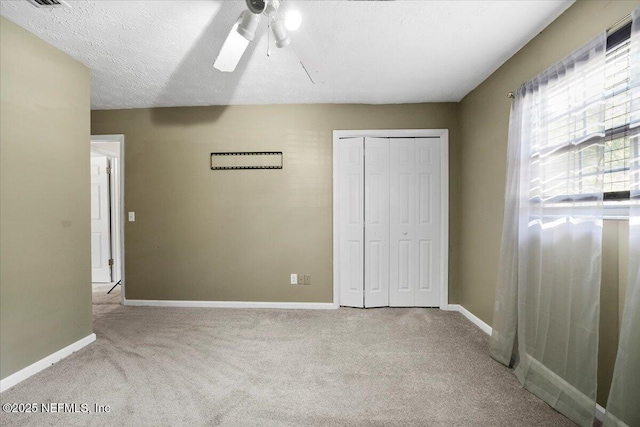 unfurnished bedroom with ceiling fan, a closet, light carpet, and a textured ceiling