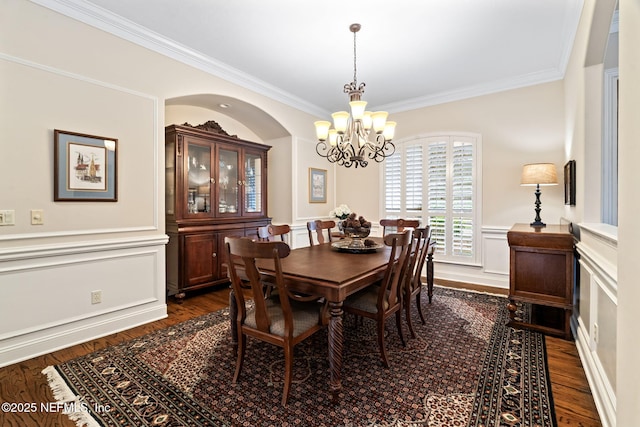 dining area featuring an inviting chandelier, ornamental molding, and dark hardwood / wood-style floors