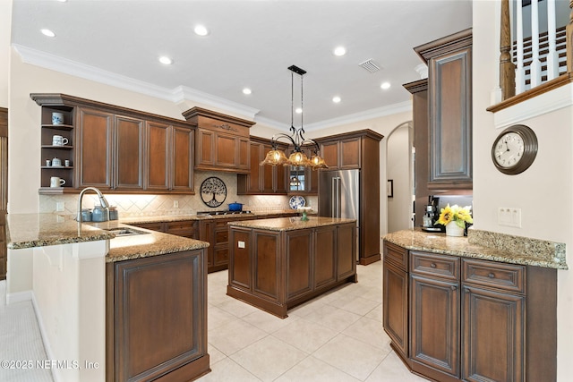 kitchen with pendant lighting, sink, backsplash, light stone countertops, and kitchen peninsula