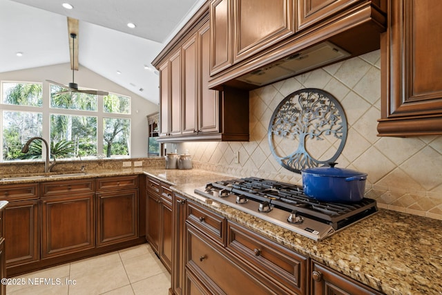 kitchen featuring light tile patterned flooring, lofted ceiling with beams, sink, stainless steel gas cooktop, and light stone countertops