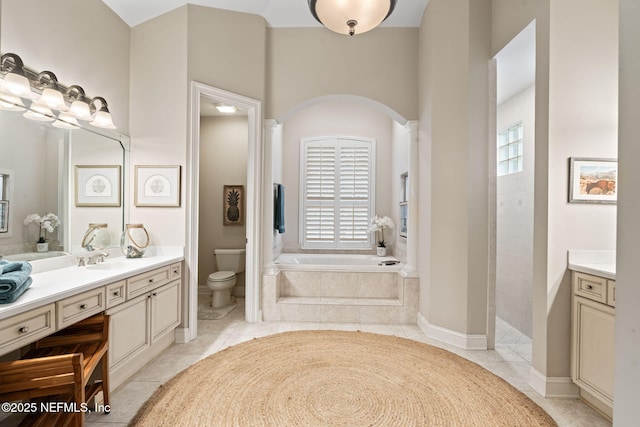 bathroom with vanity, tiled tub, tile patterned floors, and toilet