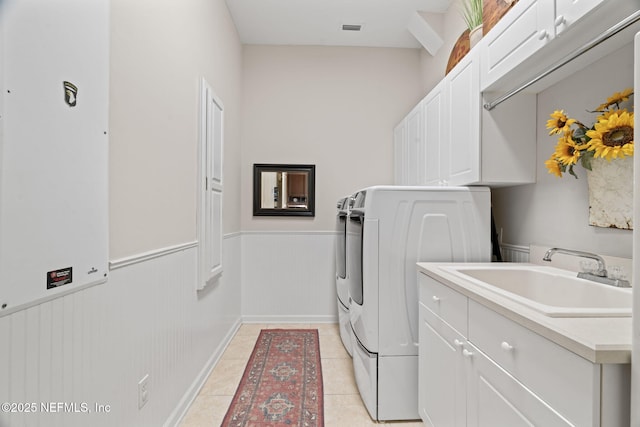 clothes washing area with cabinets, sink, light tile patterned floors, and washing machine and clothes dryer