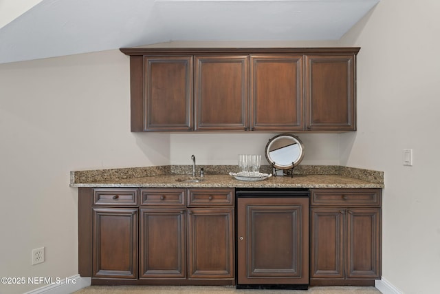 kitchen with light stone counters, dark brown cabinetry, vaulted ceiling, and sink