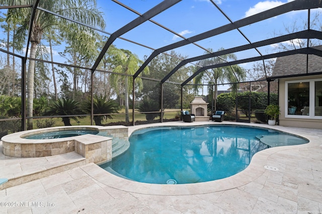 view of pool with an in ground hot tub, exterior fireplace, a patio, and glass enclosure