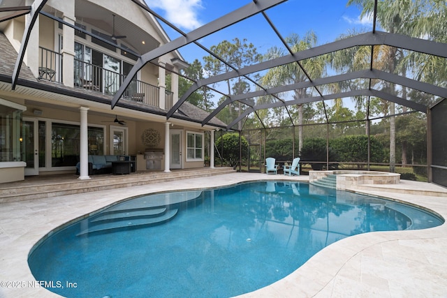 view of swimming pool featuring glass enclosure, an in ground hot tub, ceiling fan, exterior kitchen, and a patio