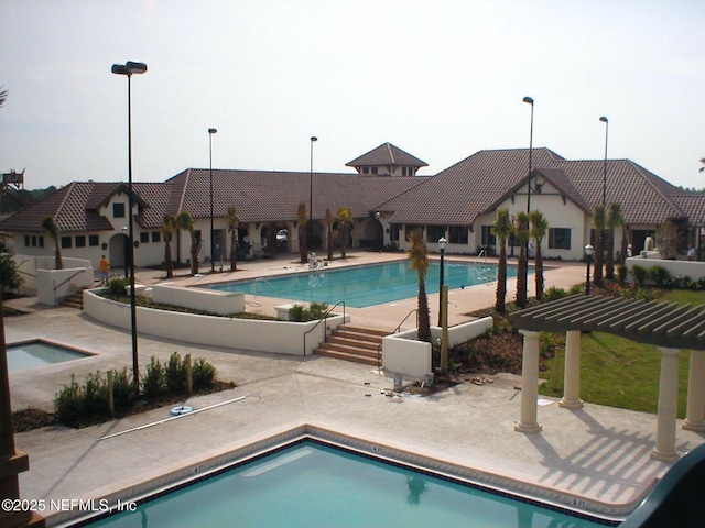 view of swimming pool featuring a pergola and a hot tub