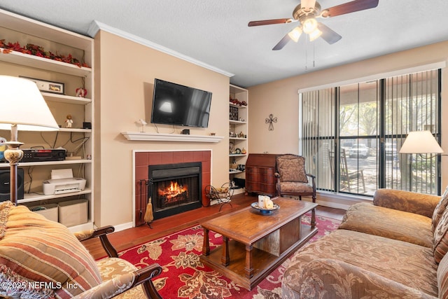 living room with ornamental molding, hardwood / wood-style floors, a tile fireplace, and a textured ceiling