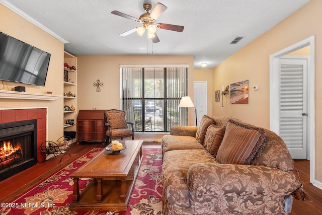 living room featuring built in features, dark hardwood / wood-style flooring, a tile fireplace, and a textured ceiling