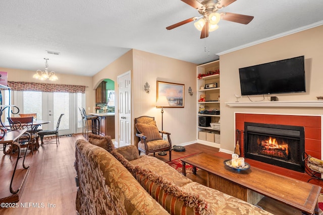 living room featuring a fireplace, wood-type flooring, built in features, and a textured ceiling