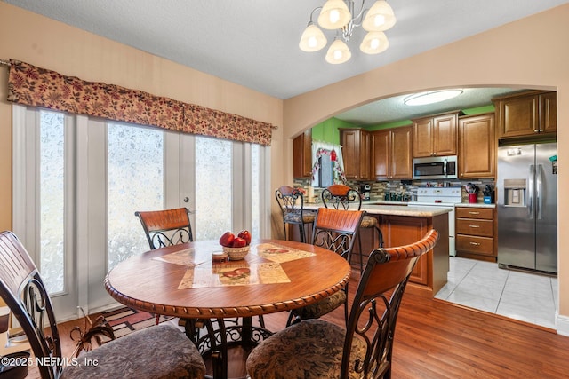 dining area with a notable chandelier, a wealth of natural light, light hardwood / wood-style floors, and a textured ceiling