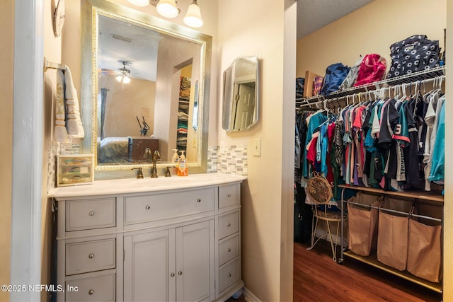 bathroom featuring hardwood / wood-style flooring, vanity, backsplash, and ceiling fan