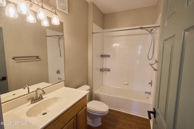 full bathroom with hardwood / wood-style floors, vanity, tiled shower / bath, and toilet