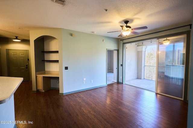 interior space with ceiling fan, dark hardwood / wood-style flooring, built in desk, and a textured ceiling