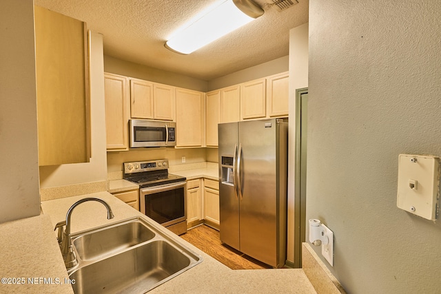 kitchen with sink, light hardwood / wood-style floors, a textured ceiling, and appliances with stainless steel finishes