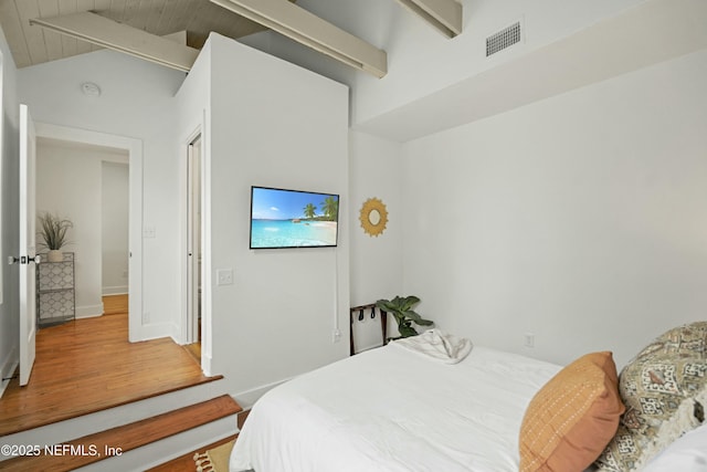 bedroom featuring vaulted ceiling with beams and hardwood / wood-style floors