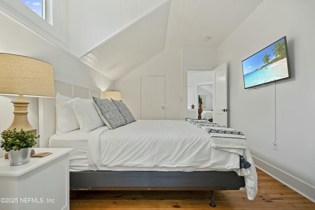 bedroom featuring hardwood / wood-style floors and vaulted ceiling